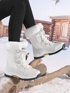 Close-up of white outdoor winter snow boots with faux fur lining on snowy cabin backdrop