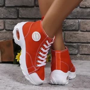Dettaglio di sneaker alte in tela arancione vivace con suola spessa platform da donna