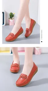 Detailopname van rode leren loafers met metalen gesp op de voeten van het model