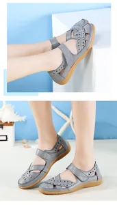 Detailansicht grauer Leder-Sandalen mit Durchbruchmuster und flacher Gummisohle.