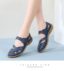 Close-up of navy blue leather hollow-out sandals with white stitching and tan sole.