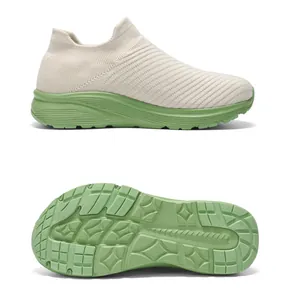 Detailed view of breathable flyknit sports sneakers with green anti-slip textured sole