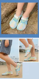 Close-up of vibrant rainbow kids water shoes worn on a sandy beach for outdoor sports.