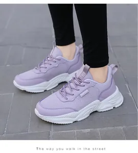 Primo piano di sneakers in mesh viola con spesse suole bianche su una strada pavimentata.