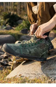 Close-up of men's camouflage waterproof winter boots in an outdoor setting.