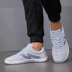 Detail of grey wide-toe casual sneakers with suede accents and durable white flat sole.