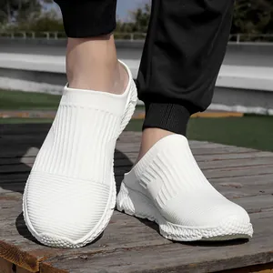 Detail view of breathable white knit slip-on sneakers on a wooden surface