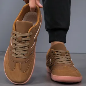 Close-up view of brown casual men's sneakers featuring a wide toe box and pink sole