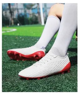 Close-up detail of professional white and red turf soccer cleats on artificial grass field