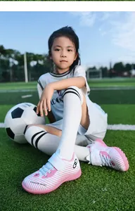 Young girl on a soccer field wearing pink and white turf soccer shoes for kids.