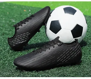 Close-up macro view of black turf soccer shoes on artificial grass with football