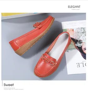 Gedetailleerd overzicht van oranje leren loafers met metalen ringen en stiksels
