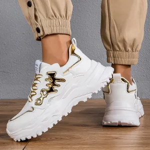 Primo piano di sneakers chunky bianche e oro con motivo a lisca di pesce su legno