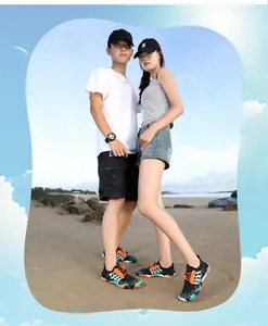 Coppia che indossa scarpe da scoglio colorate ad asciugatura rapida su spiaggia assolata