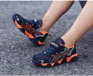 Close-up of boys' navy and orange breathable mesh sneakers on gravel ground