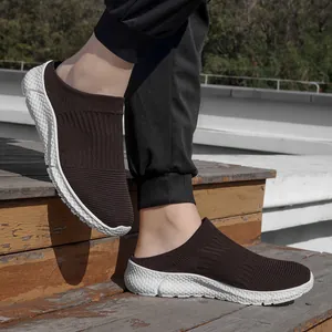 Close-up of men's brown knit slip-on sneakers with white textured soles on stairs