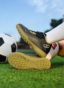 Children's turf soccer shoes with anti-slip gold sole and breathable black striped upper.