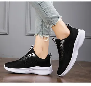 Close-up view of black breathable fly-knit women's sneakers being worn on feet.