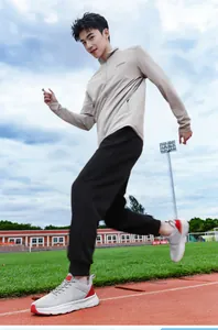 Professional male athlete running on stadium track wearing gray breathable mesh sports shoes