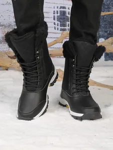 Gros plan de bottes de neige noires montantes avec doublure en fourrure chaude en hiver.