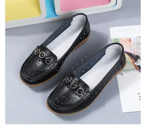 Detailopname van zwarte loafers met goudkleurige ringen en uitsparingen opzij