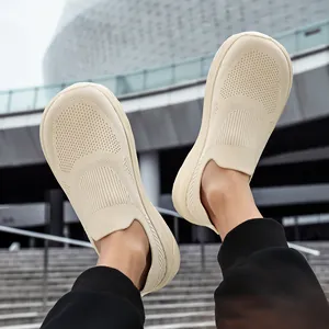 Close-up of breathable beige fly-knit slip-on sneakers with wide toe box design.