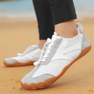 Scarpe da scoglio bianche e grigie traspiranti per uomo e donna su una spiaggia di sabbia