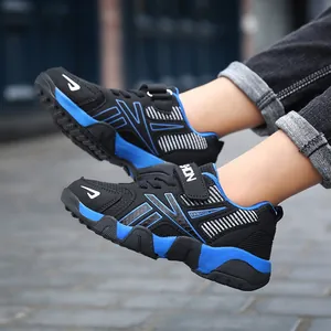 Side view of breathable black and blue boys' athletic sneakers shown on feet outdoors