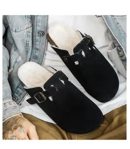 Detailed view of black suede clogs with white faux fur lining and buckle strap detail
