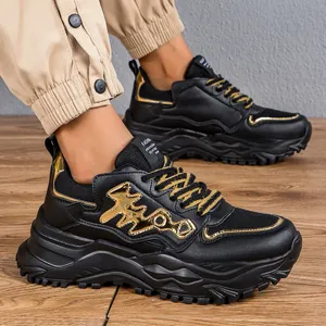 Primo piano di eleganti sneakers chunky nere e oro con design a spina di pesce su legno