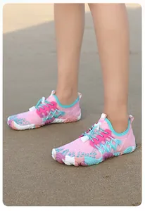 Primo piano di scarpe da acqua a piedi nudi colorate per nuoto e spiaggia sulla sabbia