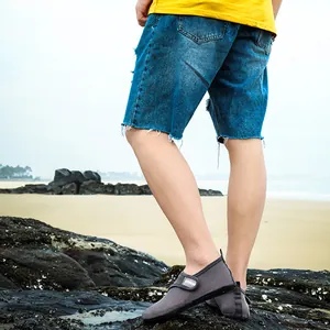 Detailed view of gray mesh water shoes with adjustable strap on rocky beach rocks