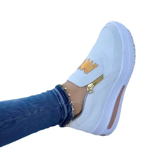 Detailed view of women's white platform sneaker featuring gold zipper and W patch.