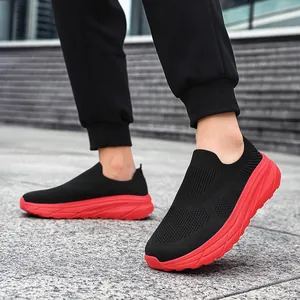 Detailed view of black breathable knit slip-on sneakers with chunky thick red soles.