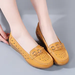 Mosterdgele lederen loafers met gatenpatroon, lage sleehak en decoratieve metalen ringen.