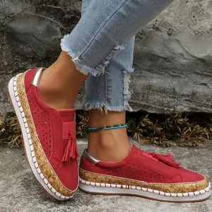 Gros plan sur des mocassins plats rouges avec glands et bordure texture liège
