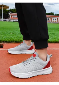 Close-up view of grey and red mesh breathable men's sports shoes on a running track