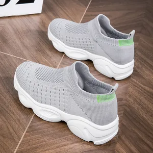 Kinder Sneaker in Grau aus Fly-Knit Material mit weicher weißer Sohle auf einem Holzboden