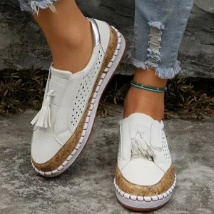 Gros plan de mocassins blancs élégants avec texture de liège et glands sur sol rocheux