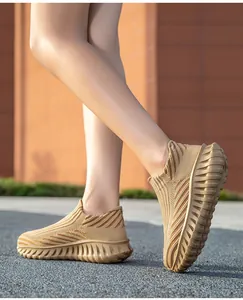Close-up side view of tan fly-knit slip-on sneakers worn by a person walking outdoors