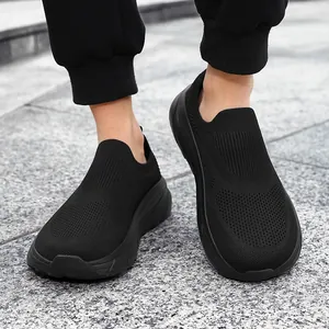 Close-up of breathable black knit slip-on sneakers for men on outdoor stone pavement