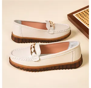 Dettaglio di mocassini beige da donna con catena dorata e suola in gomma morbida marrone