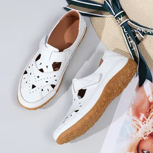 Detail view of white hollow-out flat beach sandals with a brown floral textured sole