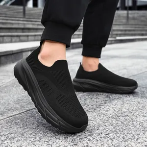 Detail view of breathable black fly-knit slip-on sneakers for men with a wide fit design.