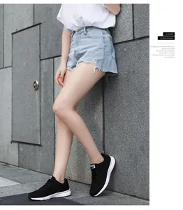 Model wearing black breathable mesh sneakers with white soles against a stone wall.
