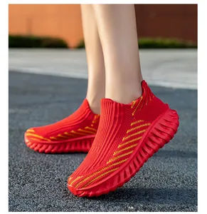 Close-up of red fly-knit slip-on sneakers with yellow stripes and textured sole