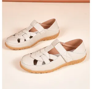 Detail showing the hollow-out design and soft beige leather of these flat sandals.