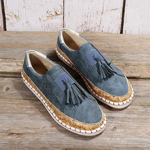 Mocassins bleus décontractés avec glands et semelle en liège sur fond de bois rustique