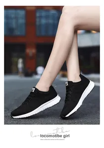 Detailed lifestyle view of black breathable fly-knit sneakers worn by model on outdoor road