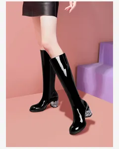 Detail view of black patent leather knee-high boots with unique transparent block heel
